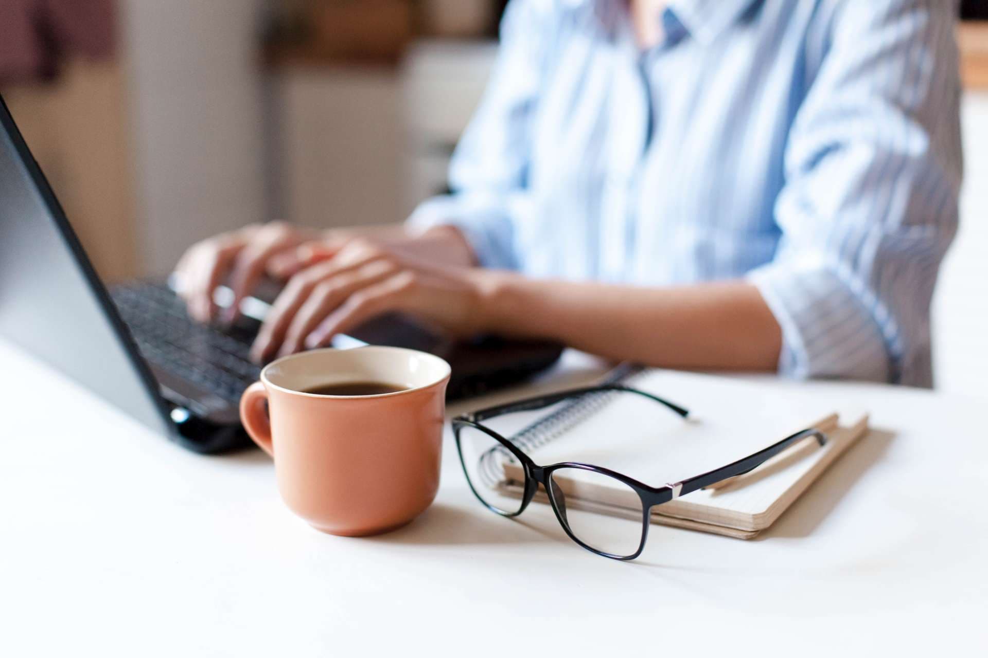 Fernarbeit von zu Hause aus. Freiberuflicher Arbeitsplatz in der Küche mit Laptop, Tasse Kaffee