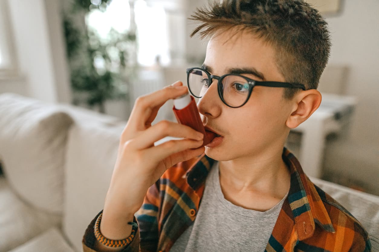 Junge auf Sofa nutzt Asthma Inhalator