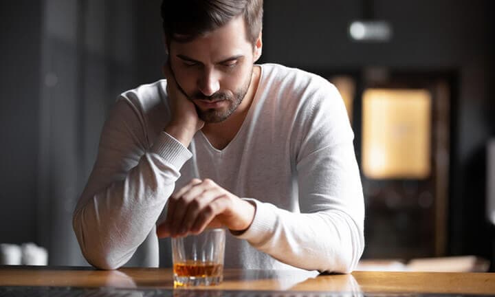 Upset man drinker alcoholic sitting with glass drinking whiskey alone