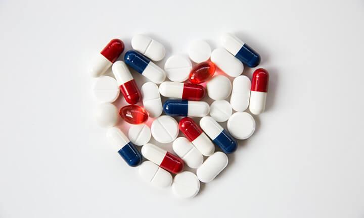 Herzpillen, Tabletten, Statine und Medikamente, die in Form eines Herzens auf weißem Hintergrund mit Kopierraum angeordnet sind