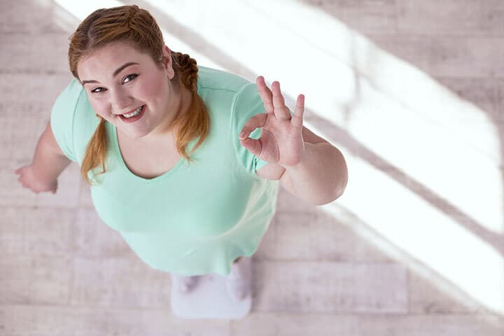 Weight check. Plump young woman checking her weight while showing the result